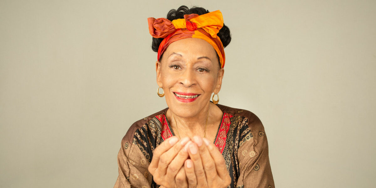 A picture of Omara in a colorful headscarf, holding out her hands.