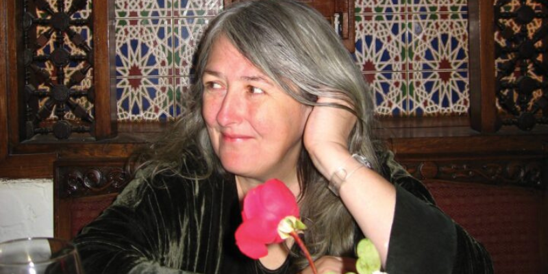 Headshot of Mary Beard (with fair skin and long grey hair) leaning her face into her hand