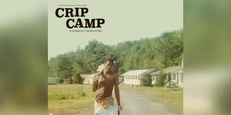 Picture of a two men, one in a wheel chair with a wide open green space behind them. Title of the movie, "Crip Camp" is listed in the left corner.