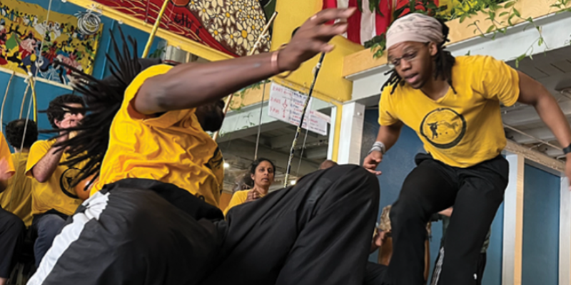 A close-up shot of two capoeira dancers mid-performance