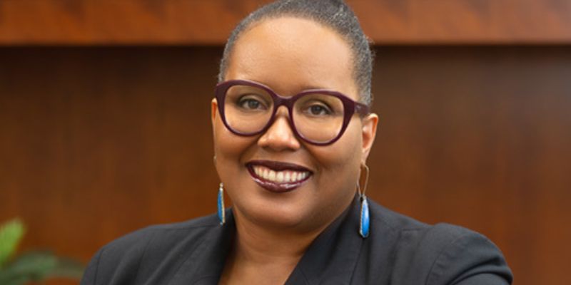 an african american woman wearing glasses smiles at the camera