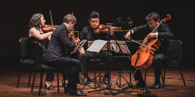 All four members of the Ehnes Quartet sit on stage in a circle and play their stringed instruments.