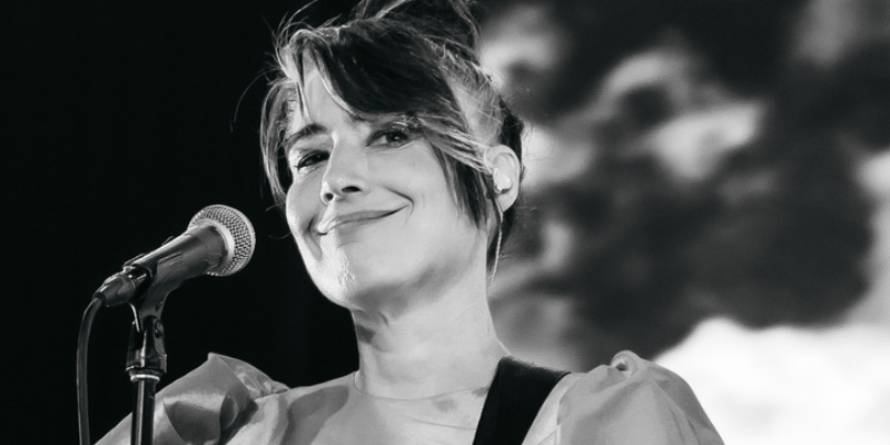 A black and white photo of Kathleen Hanna singing into a microphone