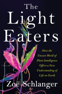 Book cover: Black background with close-up shot of a pink flower with long stamen. Main title at the top says "The Light Eaters" in big white text. The subtitle "How the Unseen World of Plant Intelligence Offers a New Understanding of Life on Earth" is to the left of the flower.
