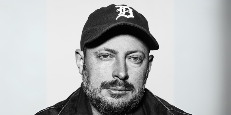 Black & white headshot of Nate Silver (with light skin, facial hair, and baseball cap)
