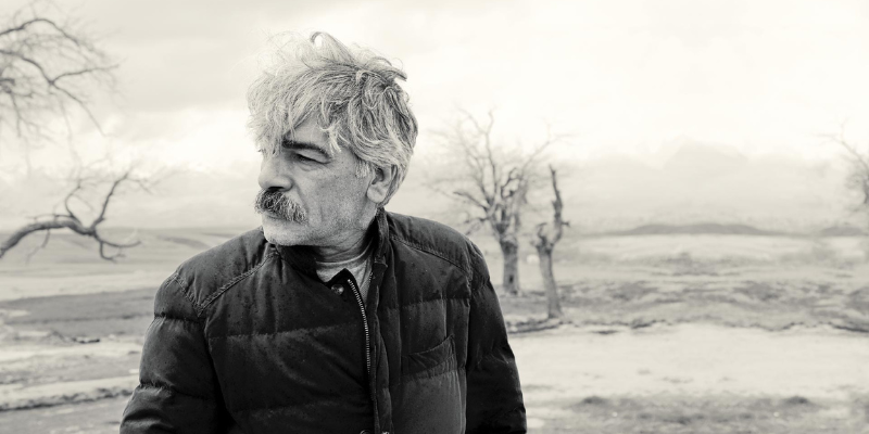 Black & white headshot of Kayhan Kahlor (with short grey hair & mustache) outdoors.