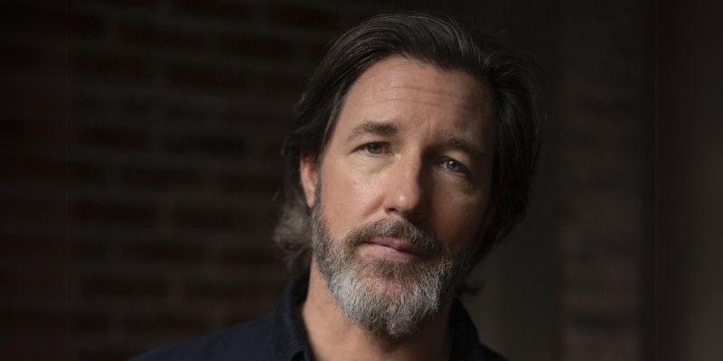 Headshot of Edward Burns (with fair skin, ear-length brown hair, and grey beard)