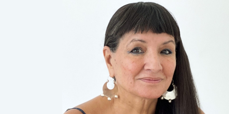 Headshot of Sandra Cisneros (with tan skin, long dark hair, and blunt bangs)