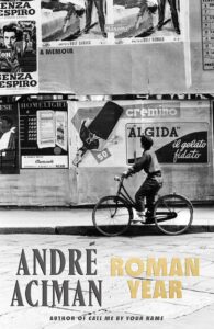 Black-and-white book cover for Roman Year by André Aciman, featuring a child riding a bicycle in front of vintage Italian movie posters and advertisements. The author's name appears in large letters at the bottom left, with the title "Roman Year" in gold and white on the right.