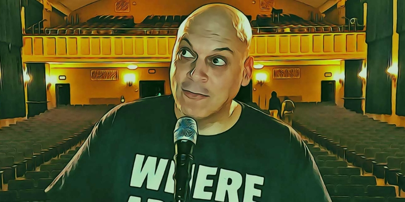 Amer Zahr poses in front of a microphone, with the empty auditorium in the background.