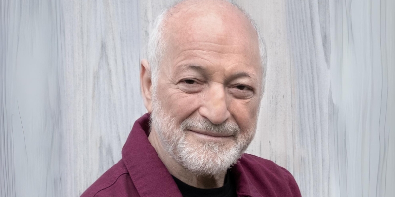 Headshot of Andre Aciman (with fair skin, white hair/beard, and red button-down shirt)