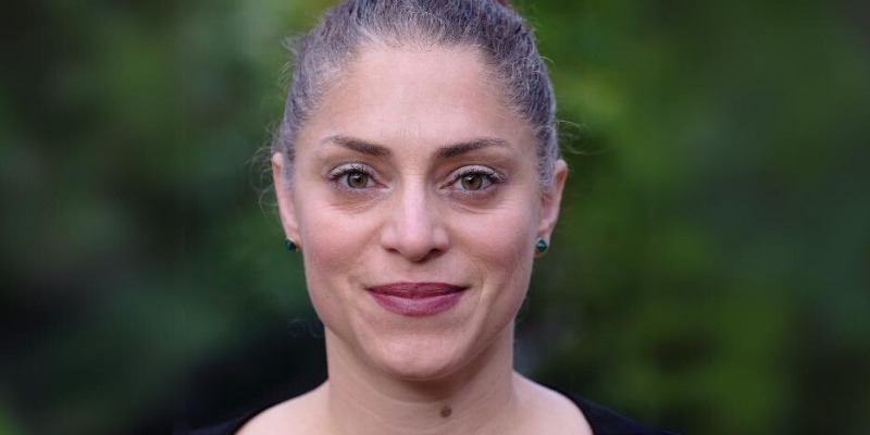 Headshot of Dr. Nooshin Razani (with light skin, green stud earrings, and grey hair updo)