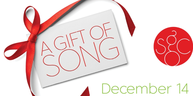 Web banner with a red ribbon-wrapped card reading 'A Gift of Song,' announcing an event on December 14. A red circular logo with 'SGC' initials appears on the right.