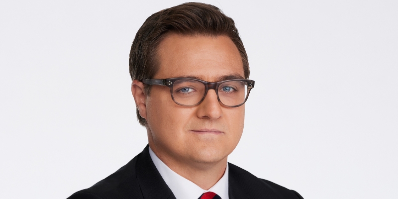 Headshot of Chris Hayes (with light skin, short brow hair, glasses, and navy suit)