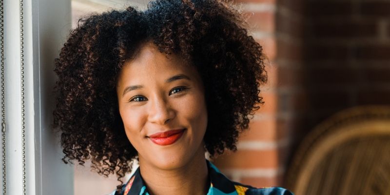 Headshot of Megan Ming Francis (with brown skin, curly black bob, and red lipstick)