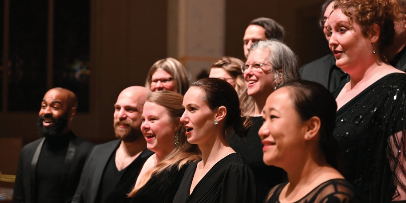 Close-up shot of a mixed choir performing, with all members wearing formal black attire.