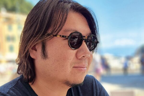 Headshot of Kevin Kwan (with light skin, short black hair, goatee, and sunglasses)