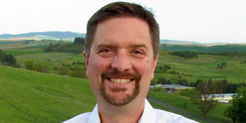 Headshot of Matthew Sutton (with short brown hair, goatee, and white button-down)