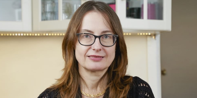 Headshot of Emily Wilson (with fair skin, shoulder length brown hair, and glasses)