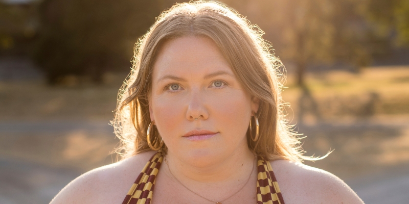 Headshot of Lindy West (with fair skin, blonde hair, and gold hoop earrings)