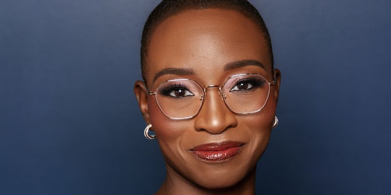 Headshot of Dr. Kemi Doll (with brown skin, shaved black hair, and eyeglasses)