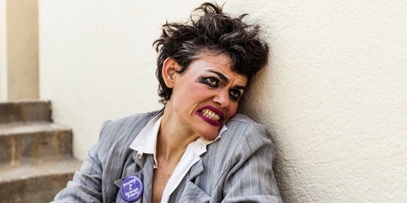 Headshot of Dynasty Handbag (with fair skin and short brown hair, wearing smudged makeup and a pin that says "Anxiety Is A Strange Friend.")