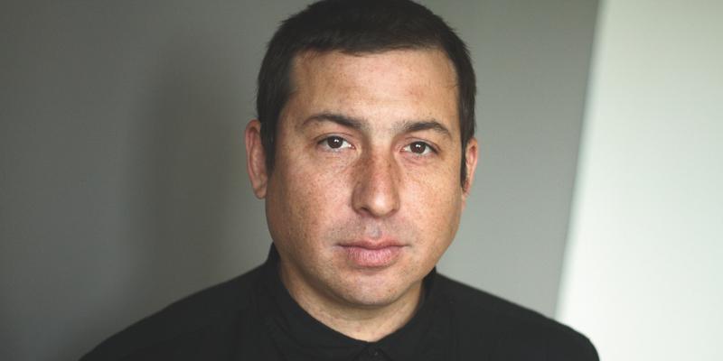 Headshot of Tommy Orange (with light skin, short black hair)
