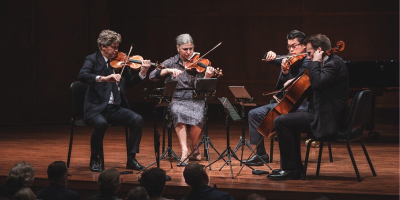 A co-ed string quartet performs on a dimly lit stage.