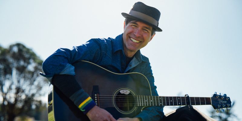 Headshot of Keeth Apgar holding the guitar and smiling
