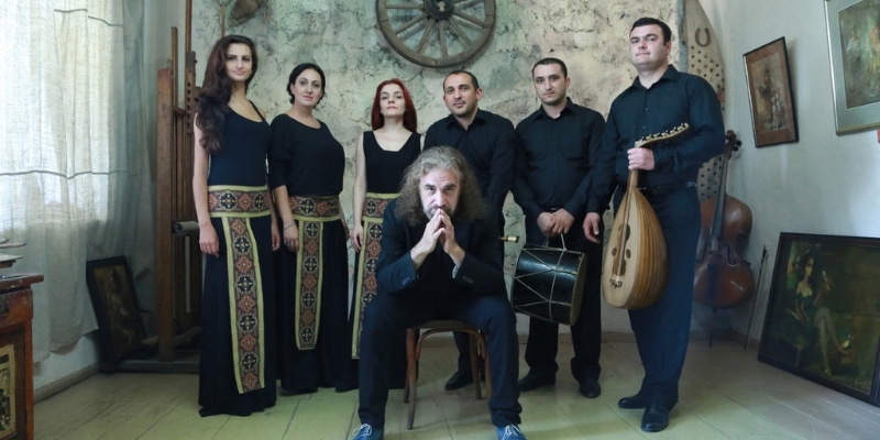 The Naghash Ensemble poses as a group in a naturally lit room wearing black clothing.